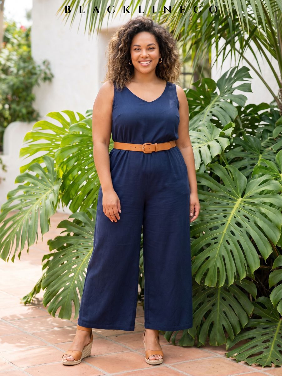 Plus size woman wearing a navy wide-leg jumpsuit with a tan belt