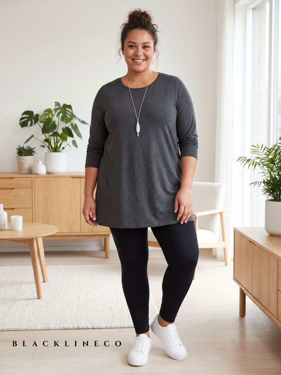 Plus size woman wearing a charcoal tunic top and black high-waisted leggings