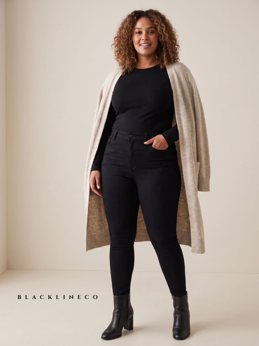 Short curvy woman wearing high-waisted black jeans, tucked-in top, and long open cardigan